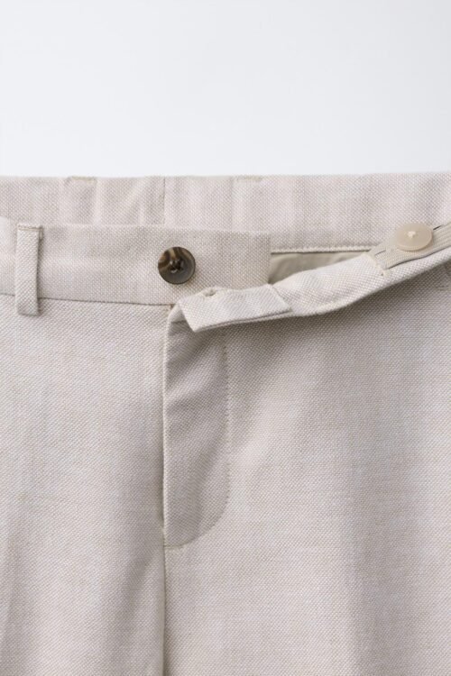 Pantalon garçon en lin beige naturel taille enfant avec bouton de fermeture visible, détail ceinture