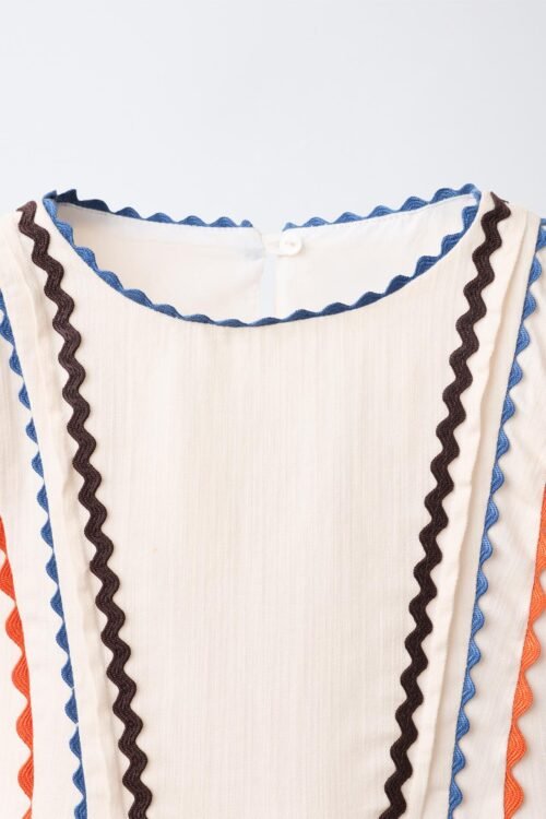 Robe fille en lin écru col rond avec galons ondulés bleu, marron et orange, détail devant