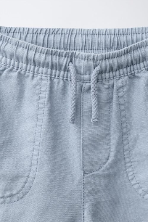 Short garçon en laine gris clair avec cordon et poches, gros plan sur la taille et la ceinture élastique