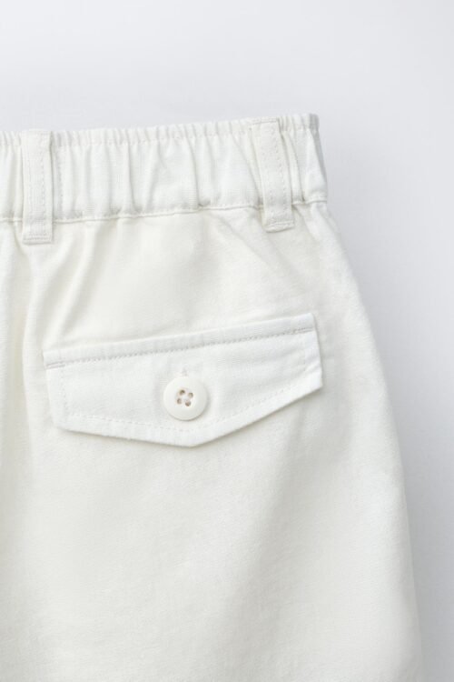 Short fille en lin naturel clair avec poche à rabat et bouton, taille enfant, détail ceinture élastique