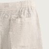 Short en lin naturel écru avec taille élastiquée et poche carrée visible, tissu léger et texturé