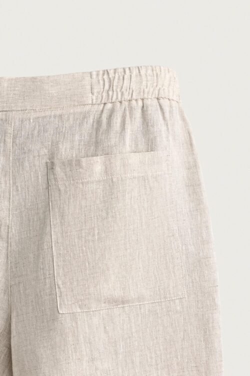Short en lin naturel écru avec taille élastiquée et poche carrée visible, tissu léger et texturé
