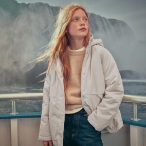Veste imperméable fille blanche à capuche portée par une enfant rousse debout face au vent
